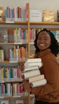 Moderatorin der Living Library, Jenny Mushegera, in einer Bibliothek mit Büchern auf dem Arm