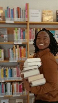 Moderatorin der Living Library, Jenny Mushegera, in einer Bibliothek mit Büchern auf dem Arm