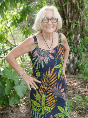 Sigrid Schell-Straub in Sierra Leone im Grünen, in einem schwarzen Trägerkleid mit großen Pflanzenornamenten.
