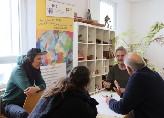 Vier Mitarbeitende diskutieren und notieren auf Flipchart Werte der Organisation.