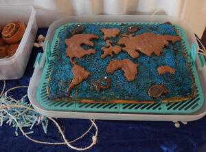 Die Welt-Torte ist blau glasiert mit Fischen und Ankern, und  Erdteilen aus Schokoladenteig