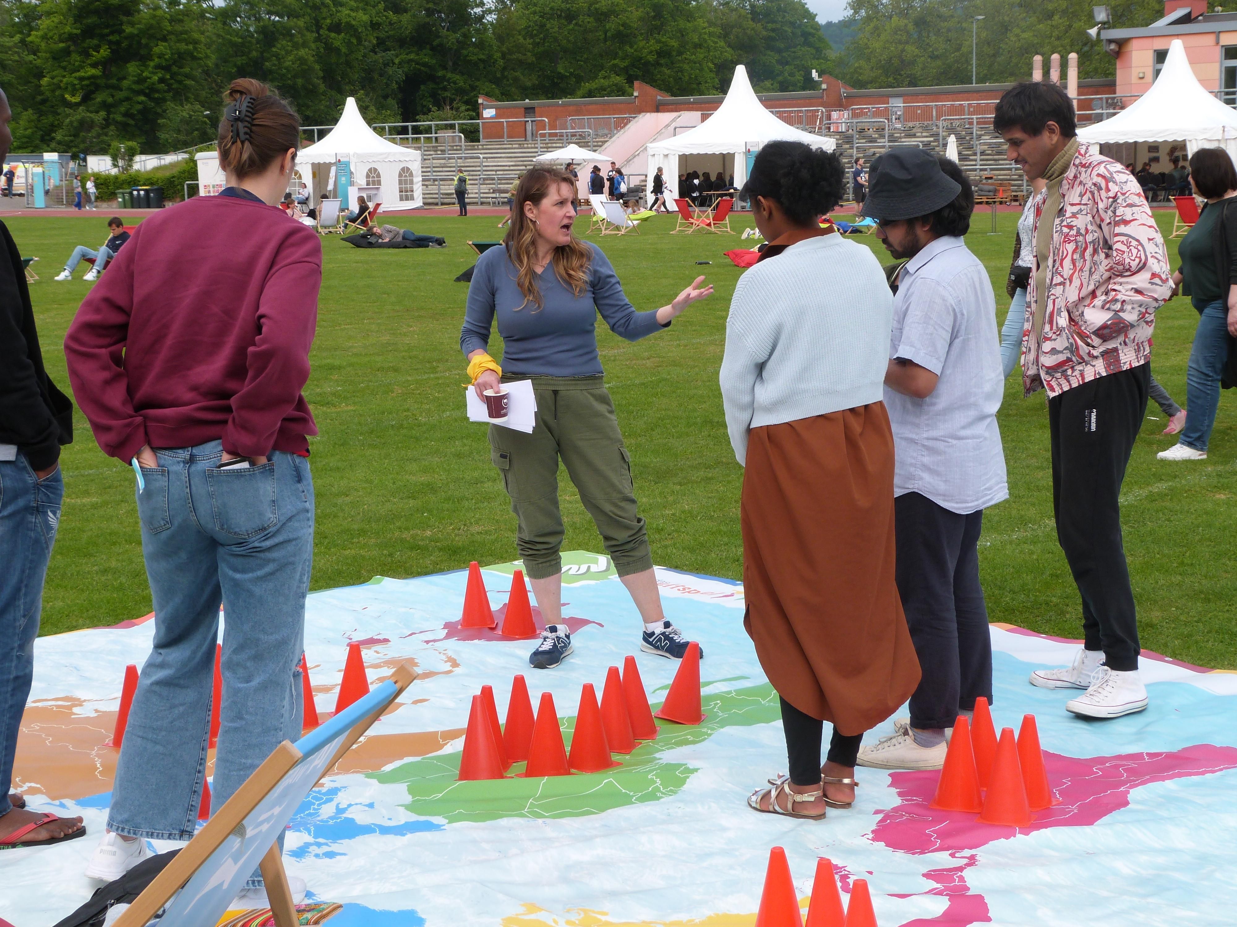 Personen stehen auf der Weltspielplane im Freien und diskutieren